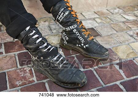 Stock Photo - A person wearing black leather boots with handwriting on. Fotosearch