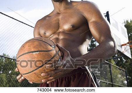 Picture - A man holding a basketball, midsection. Fotosearch