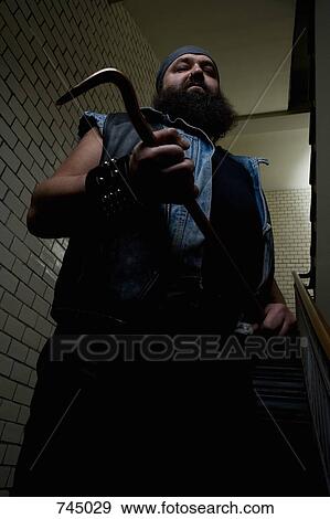 Stock Photo - A biker looking threatening and holding a crowbar. Fotosearch