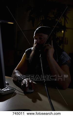 A biker sitting in a darkened office on the phone View Large Photo Image Stock Image - A biker sitting in a darkened office on the phone. Fotosearch