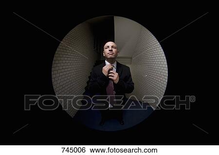 A man adjusting his tie, viewed through a peephole View Large Photo Image Stock Photograph - A man adjusting his tie, viewed through a peephole. Fotosearch