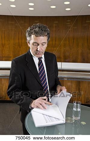 A businessman standing and looking at a document View Large Photo Image Stock Photography - A businessman standing and looking at a document. Fotosearch