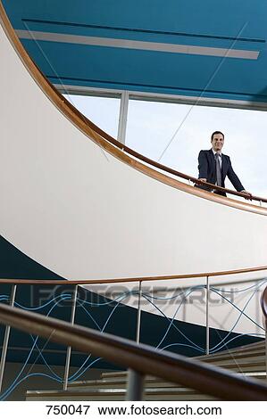 A businessman standing at the top of a staircase View Large Photo Image Stock Photo - A businessman standing at the top of a staircase. Fotosearch