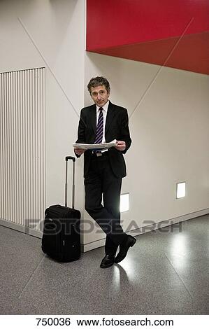 A businessman waiting with his suitcase and holding a newspaper View Large Photo Image Stock Photograph - A businessman waiting with his suitcase and holding a newspaper. Fotosearch