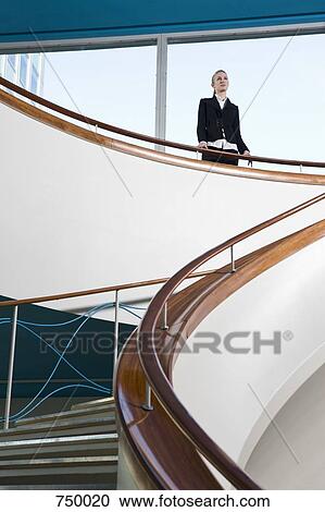 Stock Image - A businesswoman standing at the top of a staircase. Fotosearch