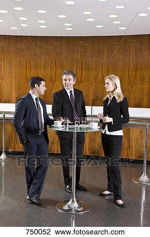 Three business people standing in a cafe View Large Photo Image Stock Image - Three business people standing in a cafe. Fotosearch