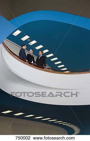Three business people standing on a balcony and talking View Large Photo Image Stock Image - Three business people standing on a balcony and talking. Fotosearch
