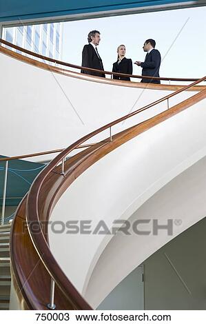 Three business people standing on a balcony and talking View Large Photo Image Stock Image - Three business people standing on a balcony and talking. Fotosearch