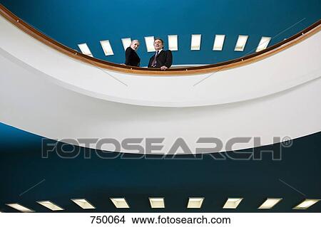 Picture - Two business people standing on a balcony. Fotosearch
