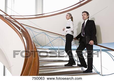 Stock Image - Two business people standing on a staircase. Fotosearch