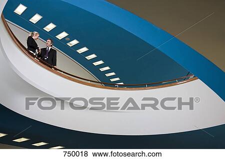 Two business people standing on a balcony and shaking hands View Large Photo Image Stock Photo - Two business people standing on a balcony and shaking hands. Fotosearch