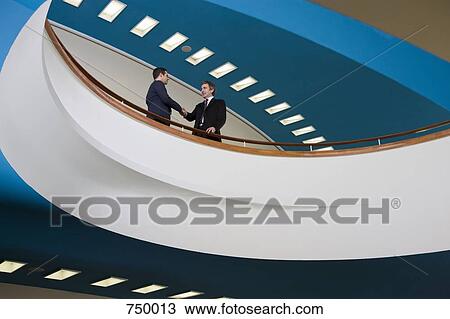 Two businessmen standing on a balcony and shaking hands View Large Photo Image Stock Image - Two businessmen standing on a balcony and shaking hands. Fotosearch