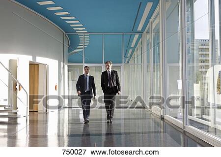 Two businessmen walking in the foyer of a convention center View Large Photo Image Stock Photo - Two businessmen walking in the foyer of a convention center. Fotosearch
