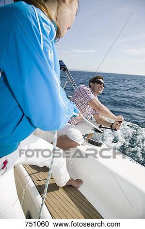 Stock Image - A couple adjusting the rigging on a yacht. Fotosearch