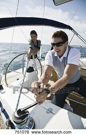 Stock Photo - A couple adjusting the rigging on a yacht. Fotosearch
