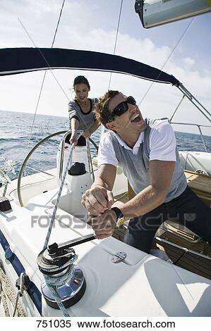 Stock Photography - A couple adjusting the rigging on a yacht. Fotosearch