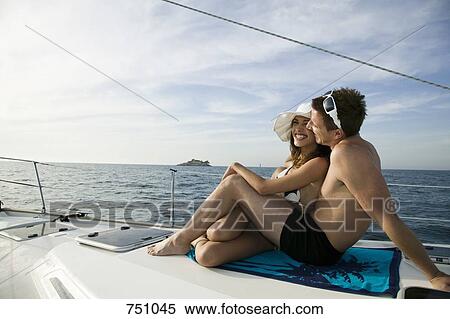 Stock Photography - A couple sunbathing together on a yacht. Fotosearch