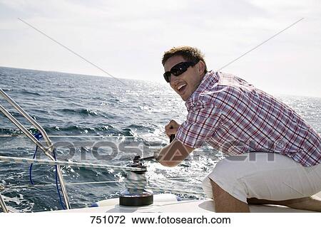 A man adjusting the rigging on a yacht View Large Photo Image Stock Image - A man adjusting the rigging on a yacht. Fotosearch