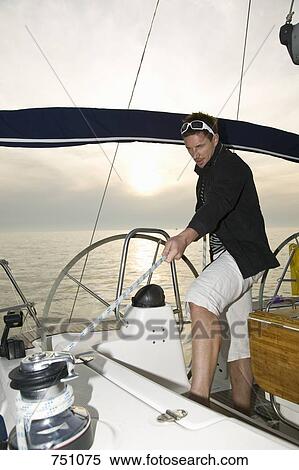 Stock Photography - A man pulling the rigging on a yacht. Fotosearch