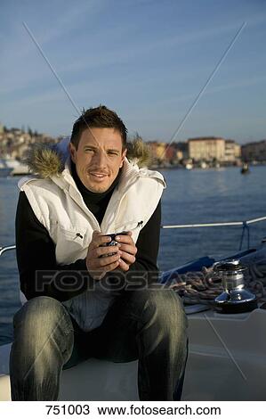 A man sitting on a yacht with a drink View Large Photo Image Stock Image - A man sitting on a yacht with a drink. Fotosearch