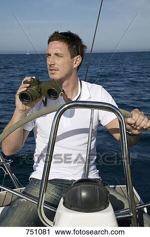 A man with binoculars at the helm of a yacht View Large Photo Image Stock Image - A man with binoculars at the helm of a yacht. Fotosearch