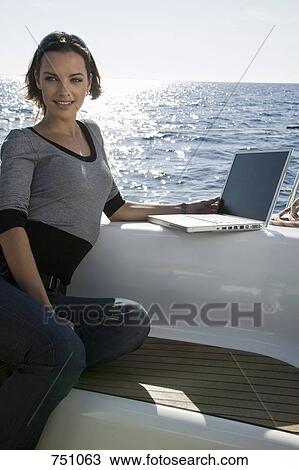 A woman using a laptop on a yacht View Large Photo Image Stock Image - A woman using a laptop on a yacht. Fotosearch