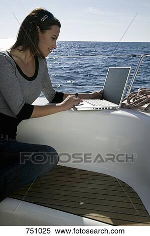 A woman using a laptop on a yacht View Large Photo Image Stock Photography - A woman using a laptop on a yacht. Fotosearch