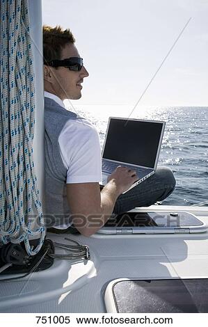Rear view of a man using a laptop on a yacht View Large Photo Image Stock Photography - Rear view of a man using a laptop on a yacht. Fotosearch
