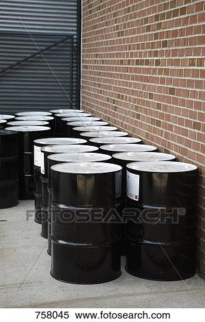 Stock Photography - Black oil drums stacked outside a building. Fotosearch