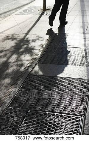 The shadow of a person walking along the street View Large Photo Image Stock Photo - The shadow of a person walking along the street. Fotosearch