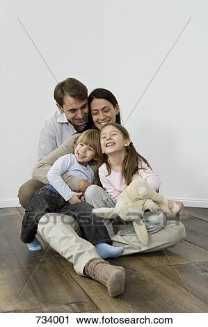 Stock Image - A family of four laughing and embracing. Fotosearch