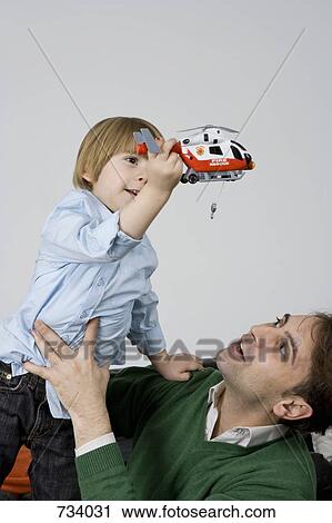 Stock Image - A father and son playing with a toy helicopter. Fotosearch
