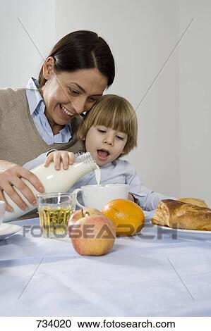 Stock Image - A mother helping her son pour milk. Fotosearch