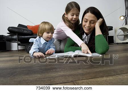 A mother reading a book to her two children View Large Photo Image Stock Photo - A mother reading a book to her two children. Fotosearch