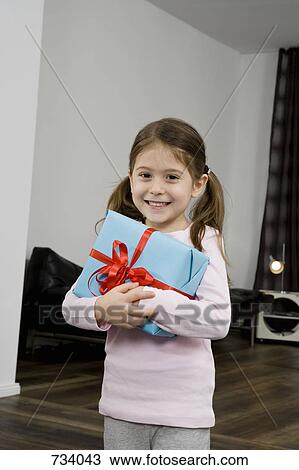 Stock Image - A young girl holding a wrapped gift. Fotosearch