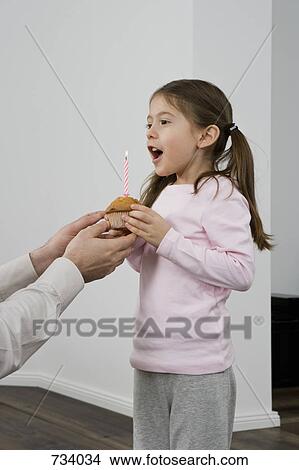 A young girl receiving a muffin with a birthday candle in it View Large Photo Image Picture - A young girl receiving a muffin with a birthday candle in it. Fotosearch