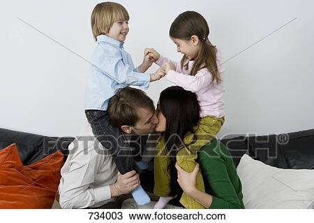 Two parents carrying children on their shoulders and kissing View Large Photo Image Stock Image - Two parents carrying children on their shoulders and kissing. Fotosearch