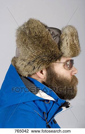 Stock Image - A man wearing warm clothing and sunglasses, profile. Fotosearch