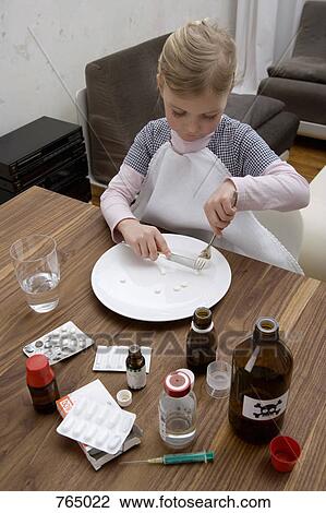 A young girl cutting a pill surrounded by medicines View Large Photo Image Stock Image - A young girl cutting a pill surrounded by medicines. Fotosearch