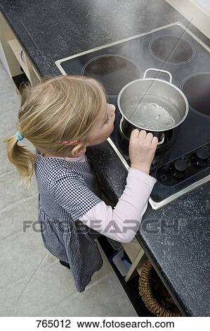 Stock Image - A young girl grabbing a pot of boiling water. Fotosearch