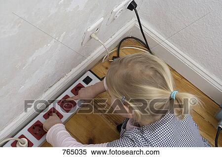 Stock Photography - A young girl touching an electric outlet. Fotosearch