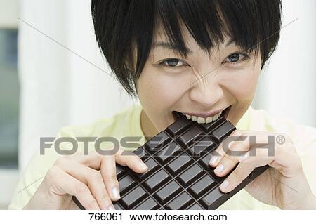Stock Image - A woman biting a chocolate bar. Fotosearch