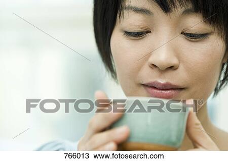 Stock Image - A woman drinking from a tea cup. Fotosearch