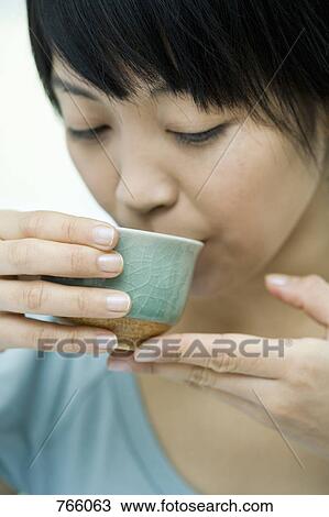 Stock Image - A woman drinking from a tea cup. Fotosearch