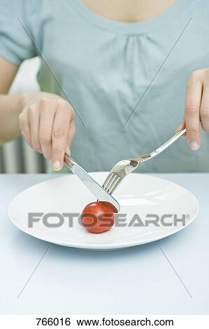 Stock Photograph - A woman eating a tomato. Fotosearch