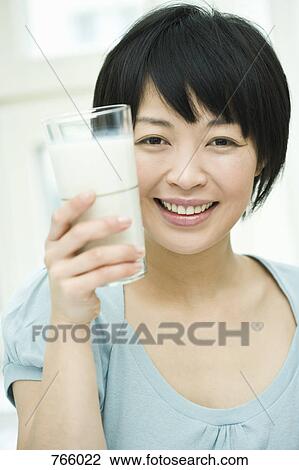 Stock Image - A woman holding a glass of milk. Fotosearch