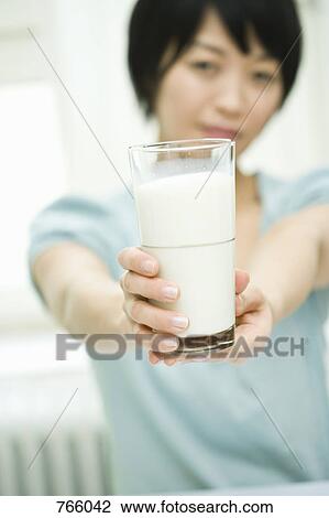 A woman holding out a glass of milk View Large Photo Image Stock Image - A woman holding out a glass of milk. Fotosearch