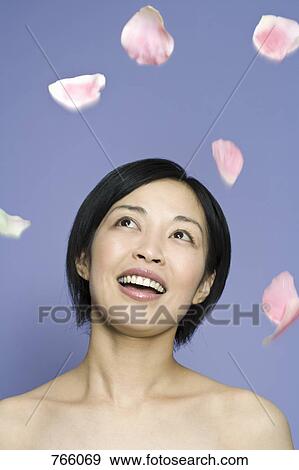 Stock Photo - A woman looking at petals falling in mid-air. Fotosearch