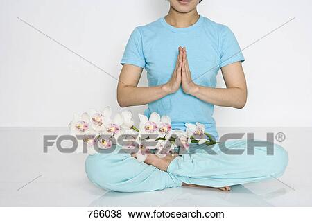 A woman sitting in the lotus position with orchids View Large Photo Image Stock Photo - A woman sitting in the lotus position with orchids. Fotosearch