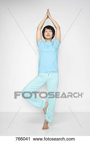 A woman standing in a yoga position View Large Photo Image Stock Image - A woman standing in a yoga position. Fotosearch